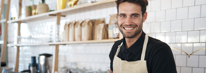 A smiling young man at his job as a barista at a coffeehouse